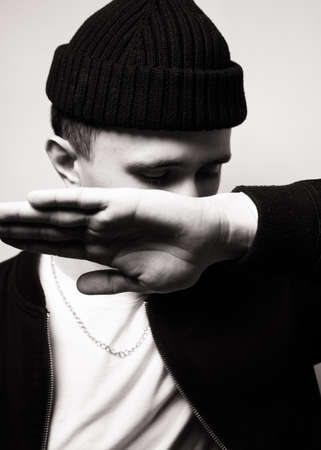portrait of young man wearing black knit hat. Black and white studio shot on white background....