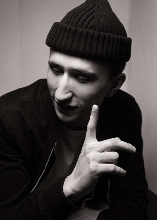 portrait of smiling young man wearing black knit hat. Black and white studio shot on white background. Teenagerhood.の写真素材