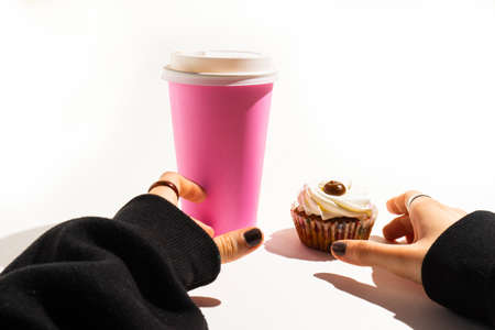 The girl's hands take a cake and a pink paper cup.の写真素材