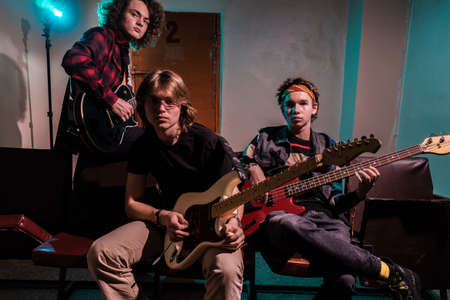 Music and fashion. Group portrait of musicians. Handsome young men holding musical instruments.の写真素材