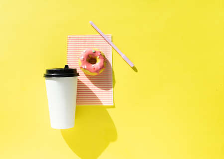 white paper cup and donut on a yellow background.の写真素材