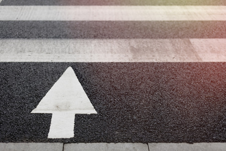 Zebra crossing and arrow signal on street at cityの写真素材