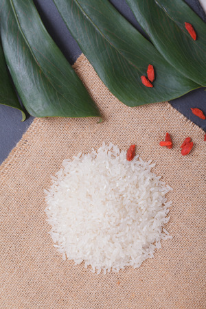 Rice isolated on black stone table with khaki linen and green leaf.の写真素材