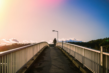 Woman riding a bicycle climbs the bridge.の写真素材