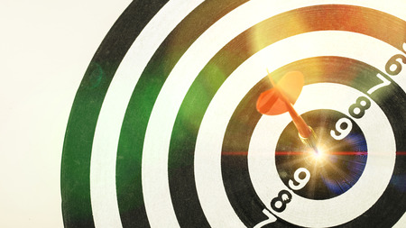 Red dart arrow hitting in the target center of dartboard with Shining light. Target business, achieve and victory concept .の写真素材
