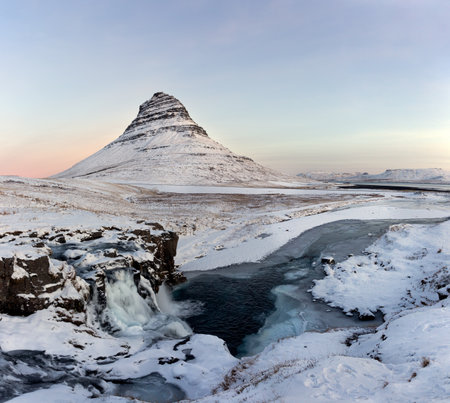 Mountain Kirkjufell in winter, Iceland, Europe. With frozen waterfall in the foreground and a covering of fresh snow at sunrise.の写真素材