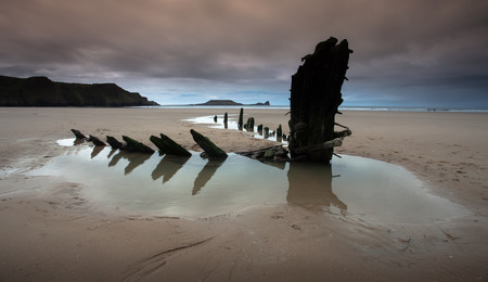 Rhossili bay is in the Gower peninsular south Wales the photo shows Worms Head on the left and the remains of the ship The Helvetia a Norwegian barque which was wrecked during a storm in 1887.の写真素材