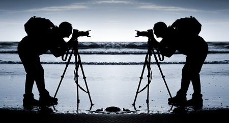 Mirror imaged silhouette of a photographer on a Gower beach in South Wales.の写真素材