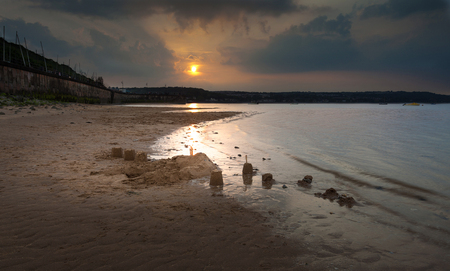 Sandcastles being washed away at a little strip of sand on Swansea Bay that's rarely exposed, near Mumbles, Swansea.の写真素材