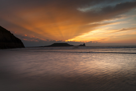 Sunset at Rhossili Bay and Worms Head on the Gower peninsula, South Walesの写真素材