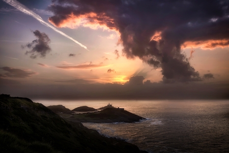 Sunrise, contrails and a mushroom style cloud over Mumbles lighthouse, Swansea, South Wales, UKの写真素材