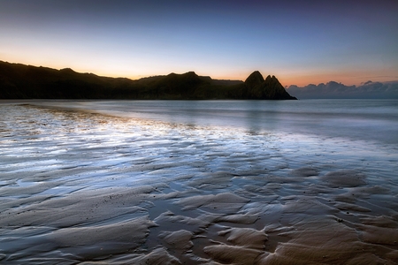 Daybreak at low tide at Three Cliffs Bay on the Gower peninsula in Swansea, South Wales, UKの写真素材