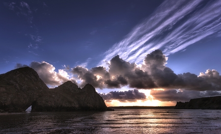Dramatic Three Cliffs Bay Sunset and back lit clouds at Three Cliffs Bay, a well known coastal beauty spot in South Gower, Swansea, South Wales, UKの写真素材