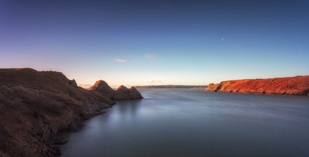 Three Cliffs Bay and the Great Tor Full tide and early Winter sun lighting up Three Cliffs Bay and the Great Tor on the Gower peninsula in Swansea, South Wales, UKの写真素材