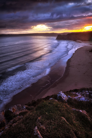 Sunset at Three Cliffs Bay and the Great Tor on the Gower peninsula in Swansea, South Wales, UKの写真素材
