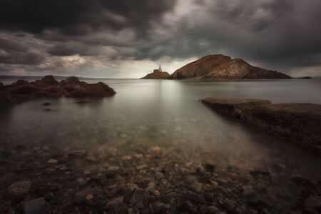 Dramatic storm clouds over Swansea Bay and Mumbles lighthouse in Swansea, South Wales UKの写真素材