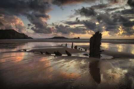 The remains of the Helvetia at Rhossili Bay, South Wales UK Rhossili Bay and Worms Head showing remains of the ship The Helvetia, a Norwegian barque, which was wrecked during a storm in 1887 on the Gower peninsula, South Wales, UKの写真素材