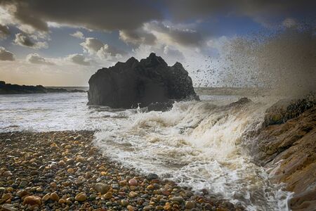 High tide, pebbles and Donkey Rock at Rotherslade, a small Bay in South Gower next to a more famous...