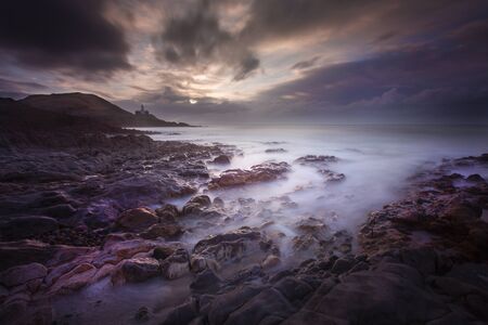 Daybreak over Bracelet Bay with a long exposure over the rock pools on the Gower peninsula in Swansea, South Wales, UKの写真素材