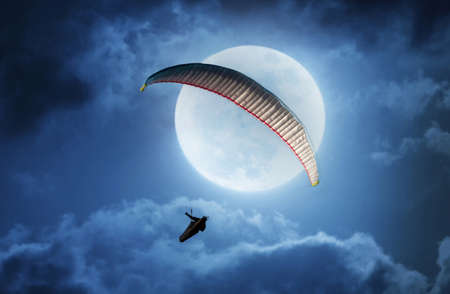 Compilation photo of a moon and someone paragliding from Rhossili Down on the Gower peninsula, South Wales.の写真素材