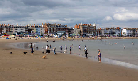 Editorial Weymouth, UK - September 11th, 2021: Holidaymakers on the gently curving arc of sand in Weymouth Bay and the Esplanade in the town of Weymouth in Dorset, England UKのeditorial素材
