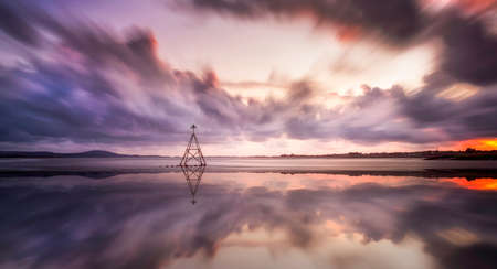 A Cardinal sailing marker at sunset on a calm tide on The Loughor Estuary, Llanelli, South Wales, UKの写真素材