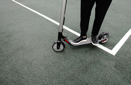 Legs of a man in stylish outfit stand on electric scooter on the streetの写真素材