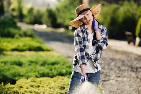 Beautiful young gardener woman watering garden in hot summer dayの写真素材