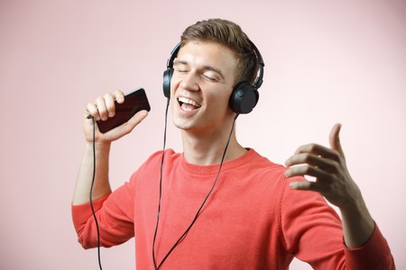 Portrait of a young handsome man with headphones smiling and listening a music with a smartphoneの写真素材