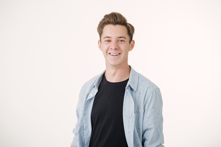 Friendly looking handsome young man wearing blue shirt smiling standing over white backgroundの写真素材