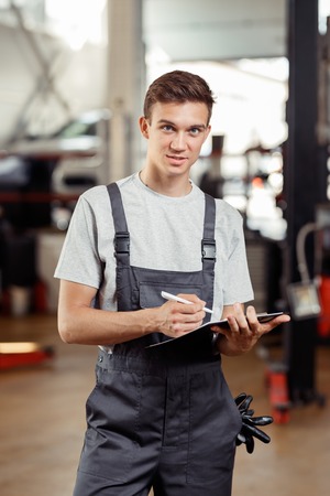 A good-looking automechanic is standing at a car service at the end of the day