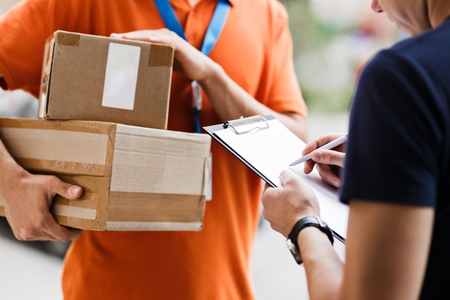 A person wearing an orange T-shirt and a name tag is deliveringの写真素材