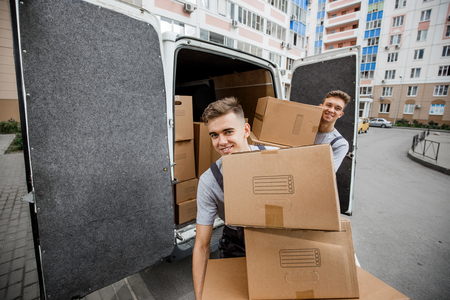 Two young handsome smiling workers wearing uniforms are unloadinの写真素材
