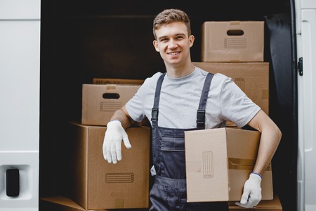 A young handsome smiling worker wearing uniform is standing nextの写真素材