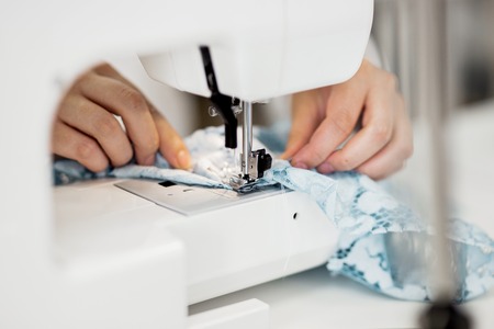 A woman is sewing with the electric sewing-machine. Fashion, tailor's workshop.