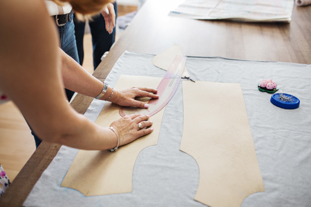 A woman with beautiful rings and bracelets is working with a sewing ruler. Fasion, tailor's...