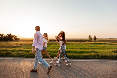 Company of happy young stylish guys walk along the road. on a sunny dayの写真素材