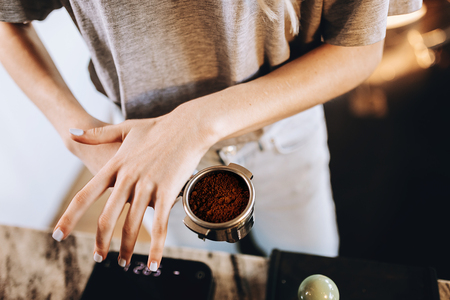 A young pretty slim girl,wearing casual outfit,is cooking coffee in a modern coffee shop. It focuses on the process.の写真素材
