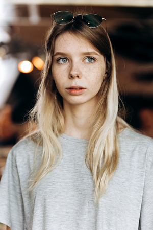 A pretty friendly slim blonde with long hair,is looking behind the camera in a cozy coffee shop.の写真素材