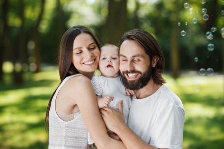 Glorious parents and their little daughter dressed in the white beautiful clothes