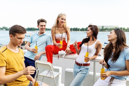 A company of good-looking friends laughing and drinking yellow cocktails in the nice cafe next to...