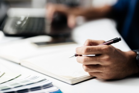 Man makes notes in a notebook on a tableの写真素材