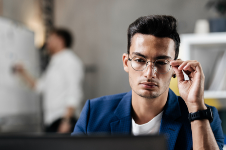 Professional young architect in glasses dressed in blue checkered jacket  works on the laptop in the officeの写真素材