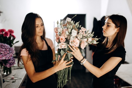 Two girls florists hold a bouquet of eustoms in pastel colorsの写真素材