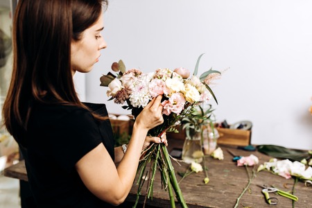 Florist girl collects beautiful bouquet of roses and asters in gentle colors in the flower shopの写真素材