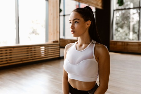 Gorgeous dark-haired girl dressed in white sports top is in the gymの写真素材