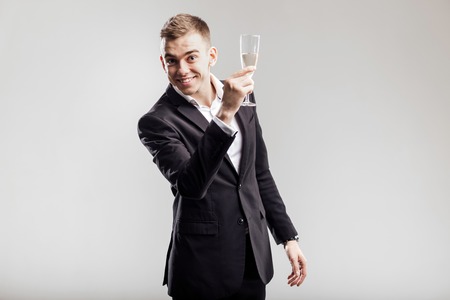 Handsome man in a business suit smiles and holds glass of champagne  on a white background. Party timeの写真素材