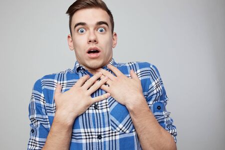 Scared  guy dressed in a plaid shirt is on a white background in the studioの写真素材