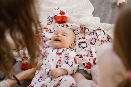 Tiny baby lies on a blanket and smiles at his momの写真素材