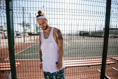 Guy with white headband  on his head and tattoos on his arms dressed in the white t-shirt, black...